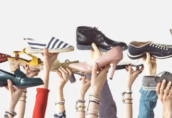 variety of hands holding up different shoes