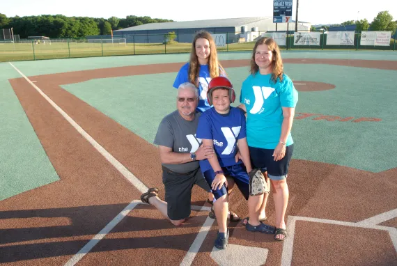 family of four posing on a baseball field
